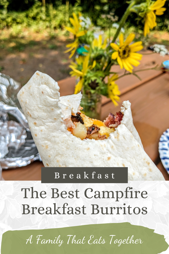 A breakfast burrito with a bite taken out of it and flowers in the background